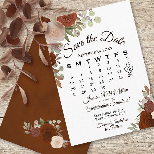 save the date card with flowers and leaves on it, next to a brown envelope