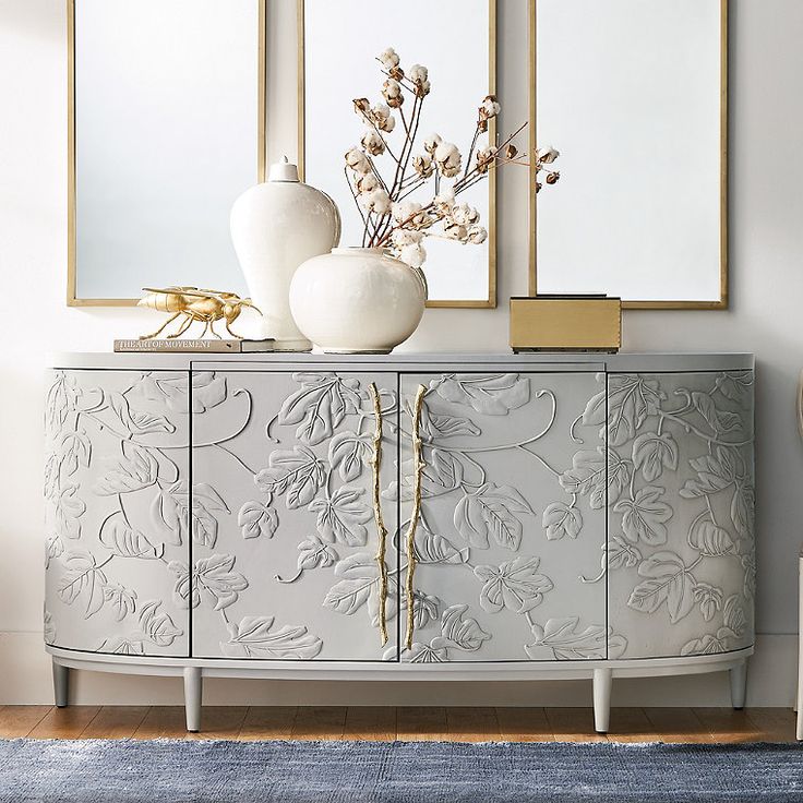 a white and gold sideboard with two vases sitting on it's sides