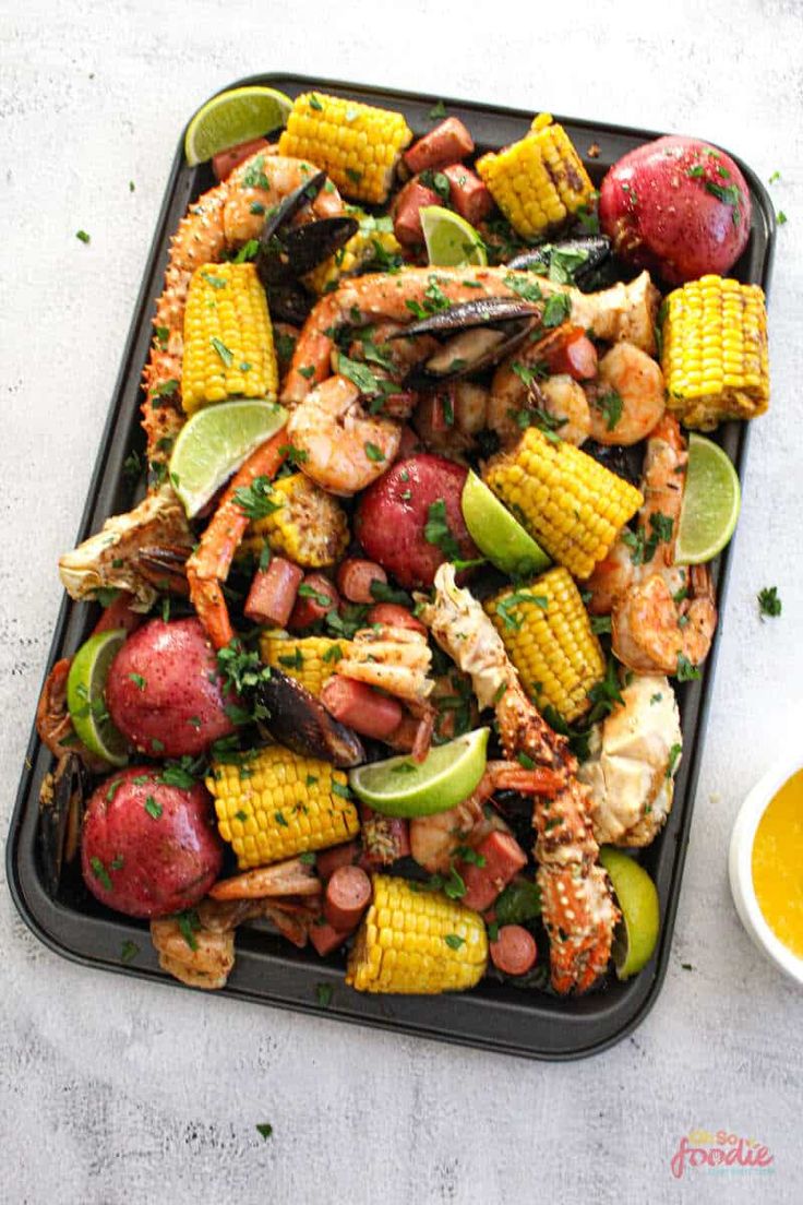 a tray filled with shrimp, corn and potatoes