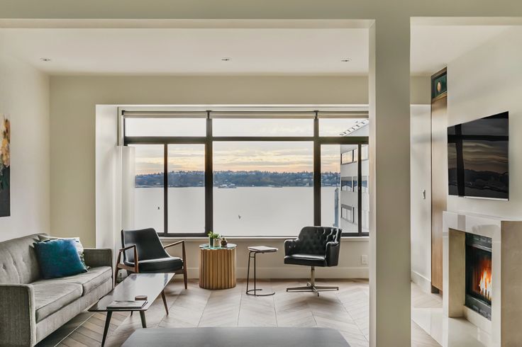 a living room filled with furniture and a fire place in front of a large window