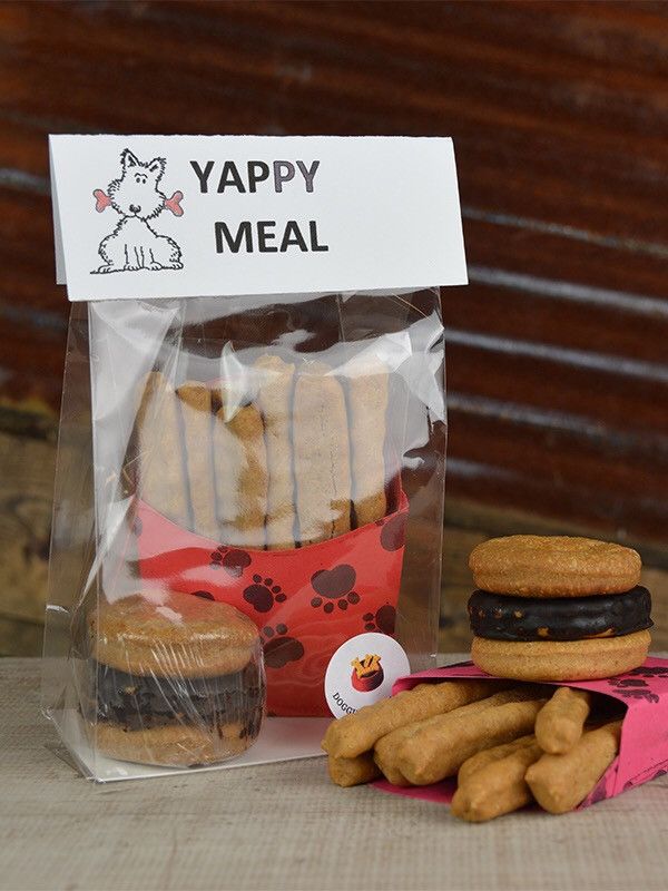 a package of dog treats next to a bag of cookies on a table with a sign that says happy meal