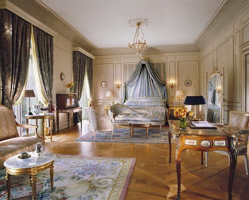 an elegant bedroom with white walls and gold trimmings, decorated in antique furniture