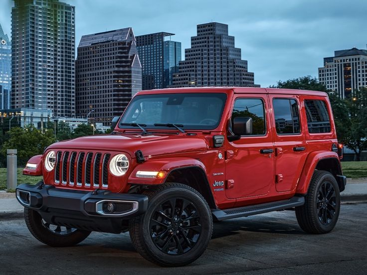 a red jeep parked in front of a city skyline