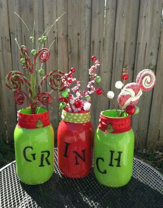 three mason jars with candy canes and candies in them on a table outside