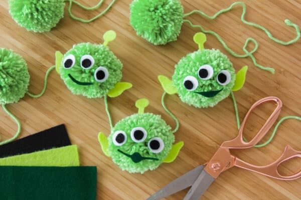 some green pom poms and scissors on a table