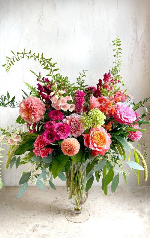 Eclat de Couleurs- Fall floral arrangement. This lovely arrangement stands tall with locally grown dahlias and bursts of bright colors. Orange and different shades of pink with whimsical greens in a tall glass vase. Pink Flowers Arrangements Vase, Flowers In Vase Arrangement, Vivid Flower Arrangements, Bright Fall Floral Arrangements, Tall Vase Bouquet, Spring Table Flowers, Multicolor Floral Arrangement, Dahlia Flower Arrangements Centerpieces, Dahlia Vase Arrangement