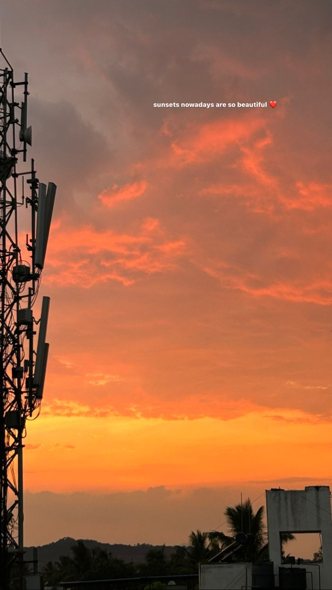 the sun is setting behind a tower with cell phones on it's sides and palm trees in the foreground