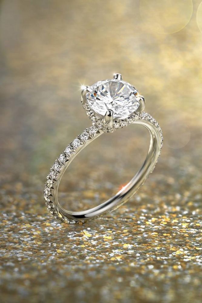 an engagement ring with diamonds on the bottom and side stones in the middle, sitting on a glittery surface