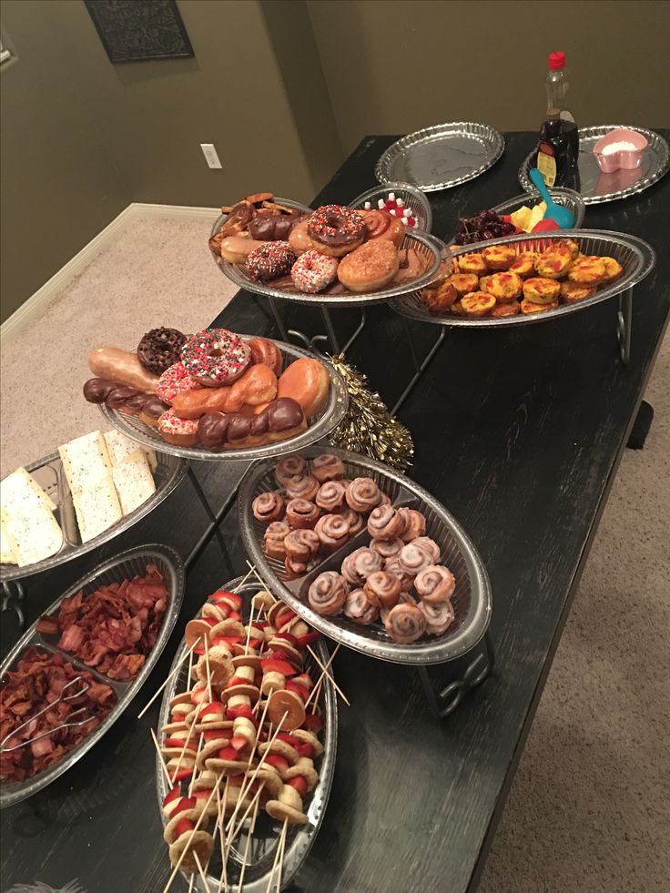 a table topped with lots of trays filled with different types of donuts and pastries