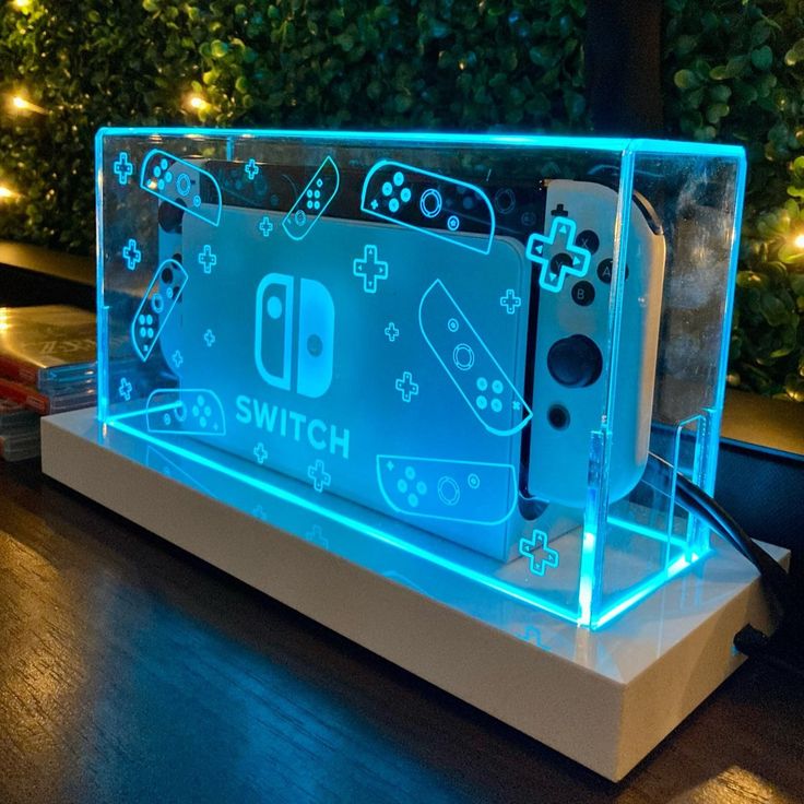 an illuminated display case with video game controllers in the front and behind it, on a wooden table