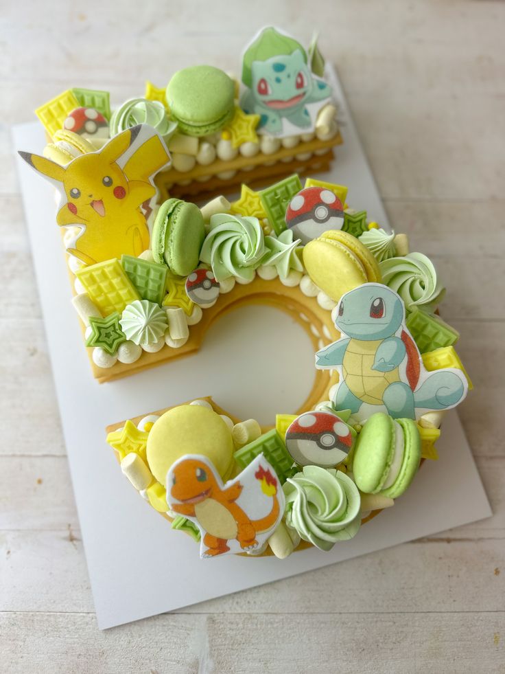 two decorated cookies sitting on top of a cutting board with the letter e spelled out