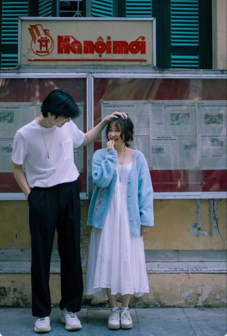 two people are standing in front of a store window and one is touching the other's hair