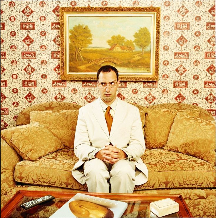 a man sitting on top of a couch in front of a painting