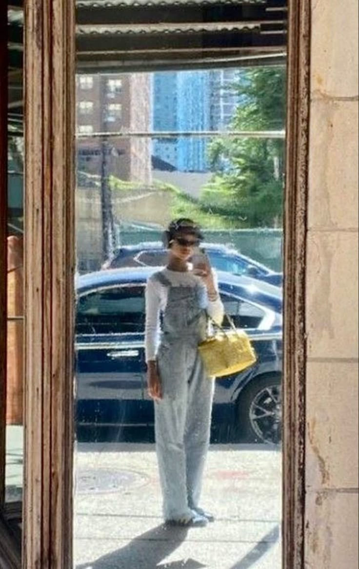 a woman standing in front of a mirror holding a cell phone up to her ear