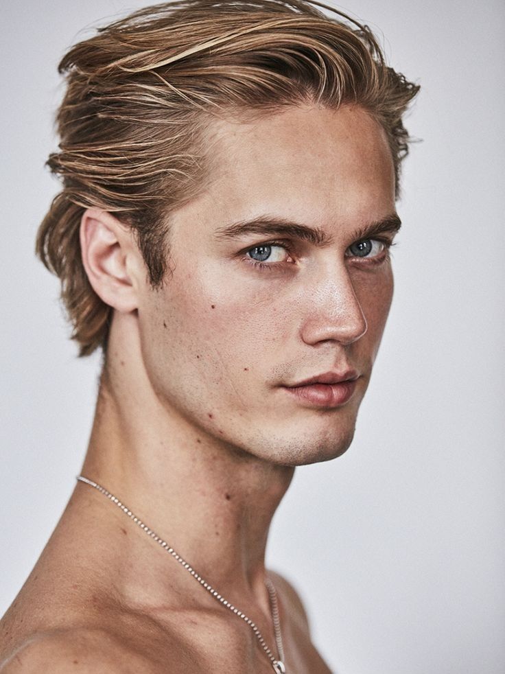 a young man with blue eyes is posing for the camera, wearing a necklace and no shirt