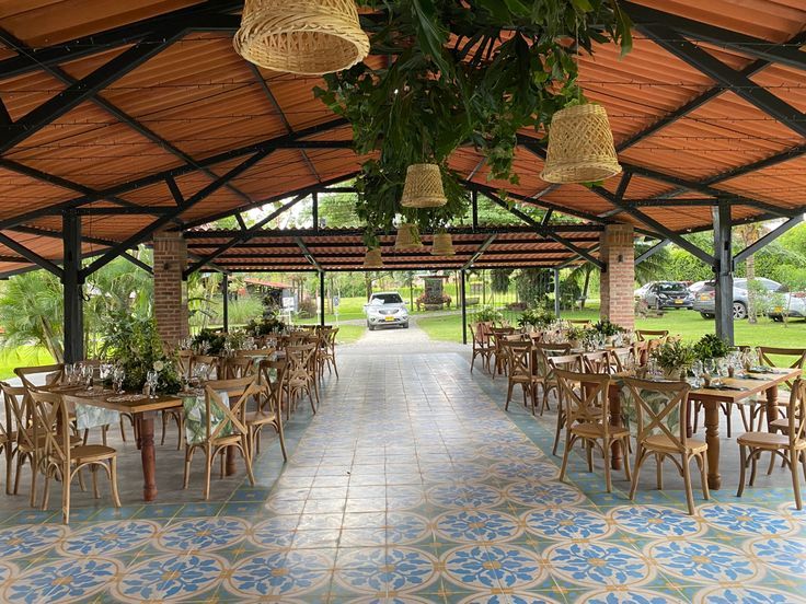 an outdoor dining area with tables, chairs and hanging baskets on the ceiling is shown