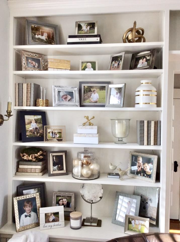 a bookshelf filled with pictures and other items on top of a white shelf