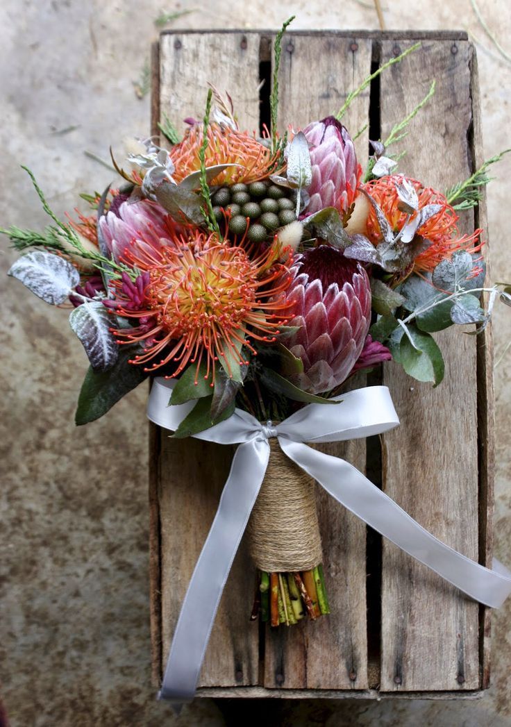 a bouquet of flowers sitting on top of a wooden crate next to a white ribbon