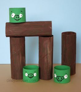 three green piggy cups sitting next to each other on a wooden table with blue wall in the background