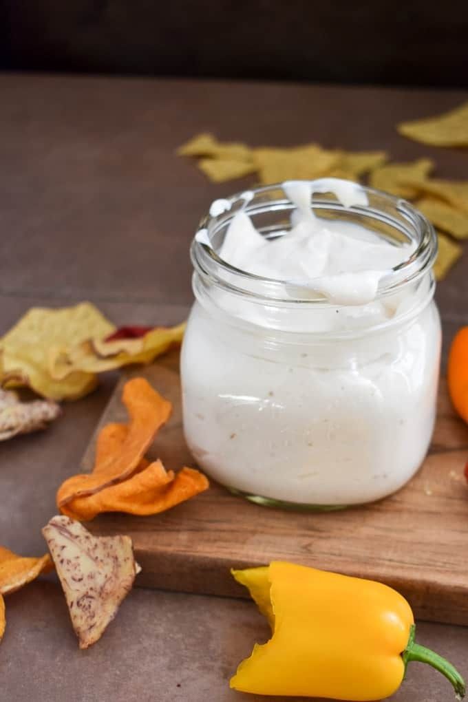 a jar filled with whipped cream sitting on top of a wooden cutting board next to oranges