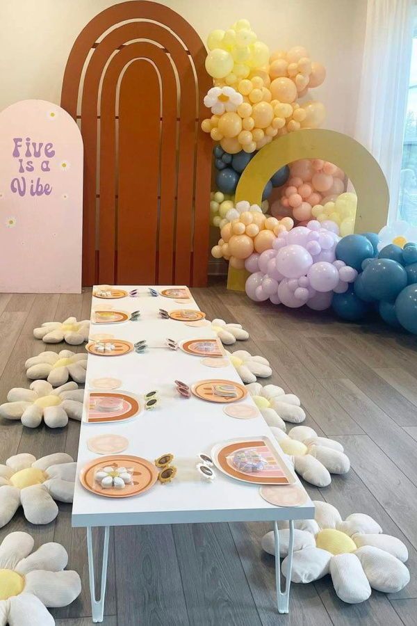 a table set up for a party with balloons and plates laid out on the floor