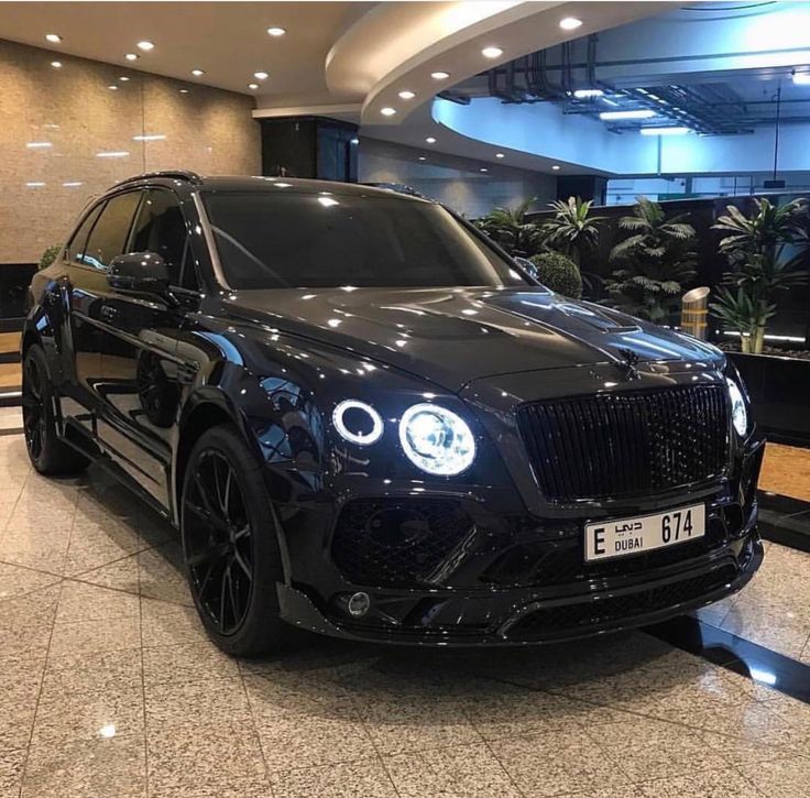 a black car is parked in the middle of a mall floor with other cars behind it