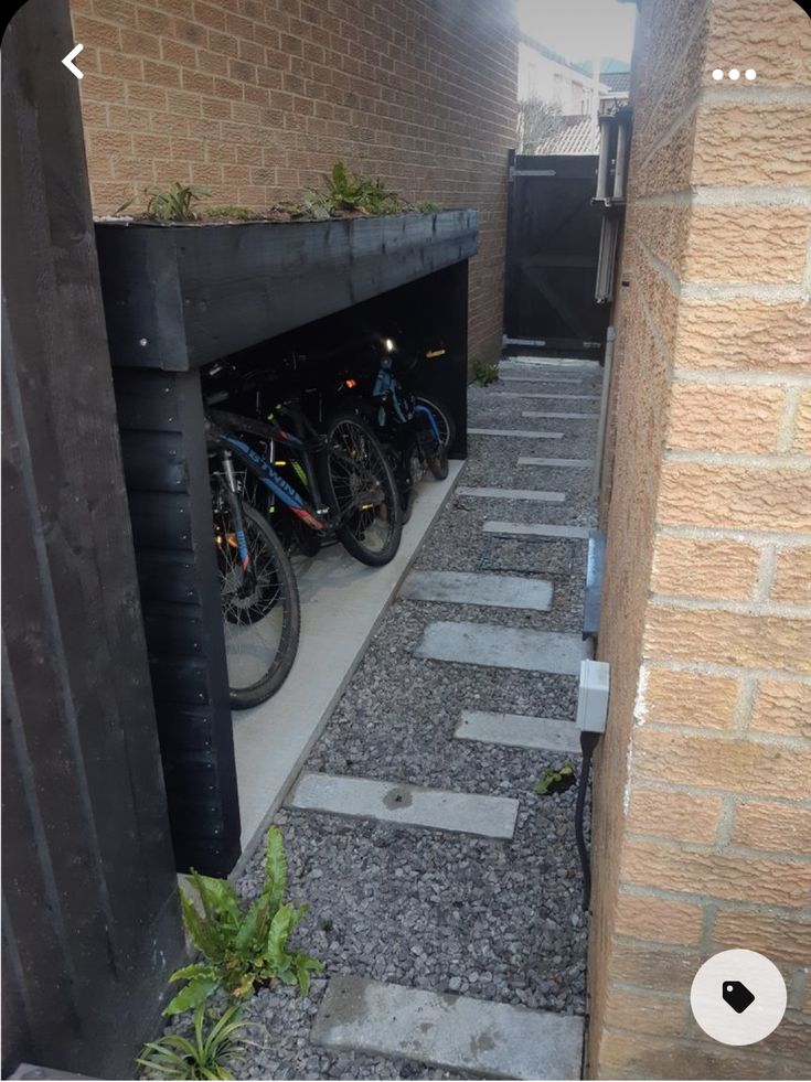 there are many bikes parked in the bike storage area on the sidewalk near the building