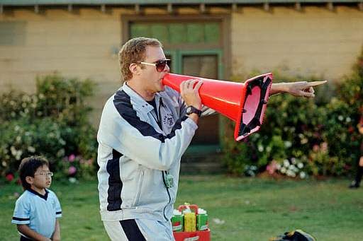 a man holding a red and black megaphone in front of other people on the grass