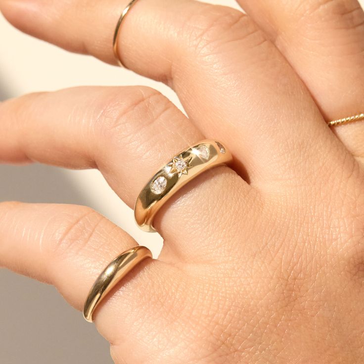 a woman's hand with two gold rings on top of her finger and one in the middle