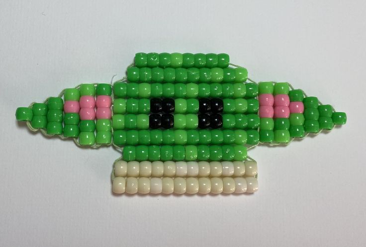 a green and white beaded brooch sitting on top of a table