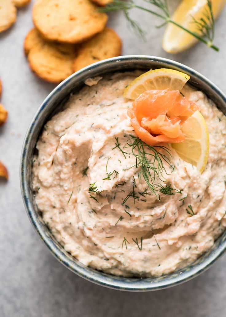 a close up of a bowl of hummus with lemon wedges