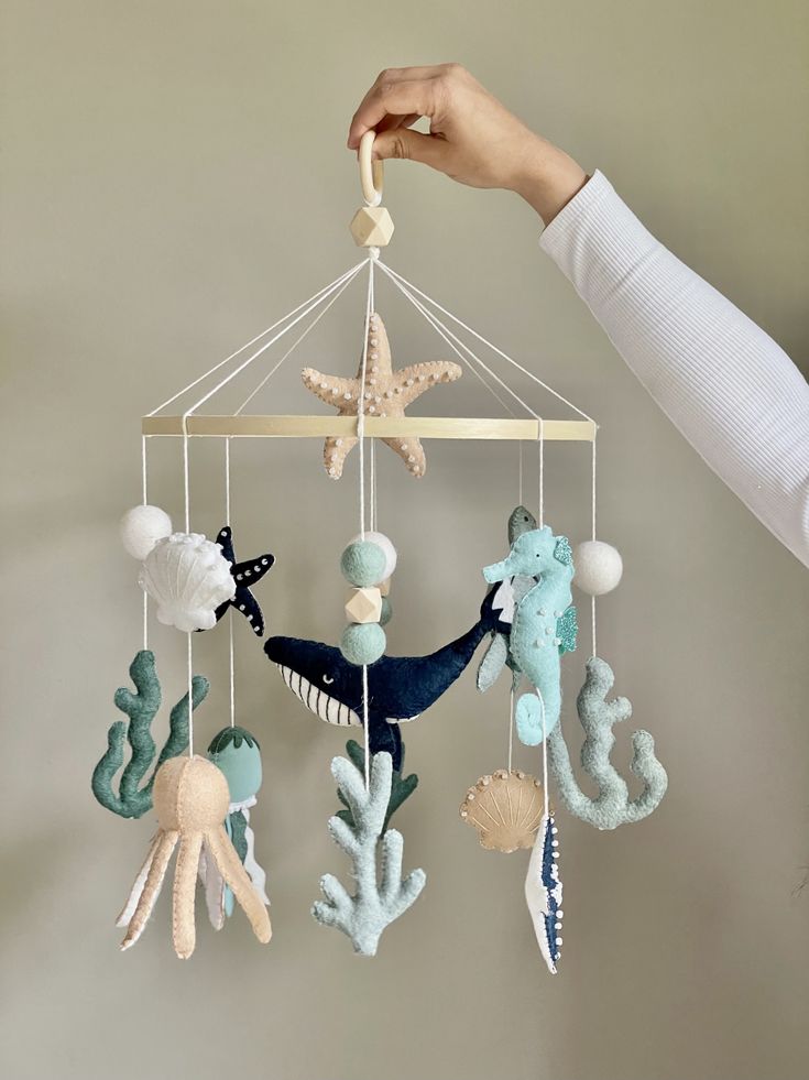 a person is holding up a mobile with sea animals and stars hanging from it's sides