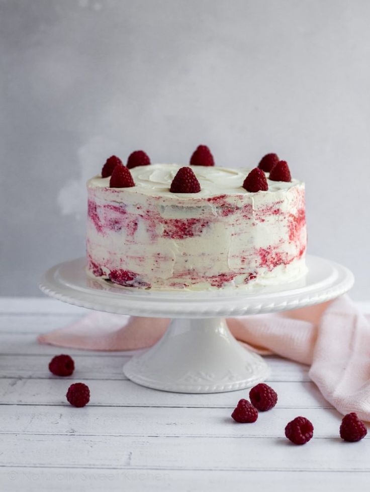 a white cake with raspberries on top