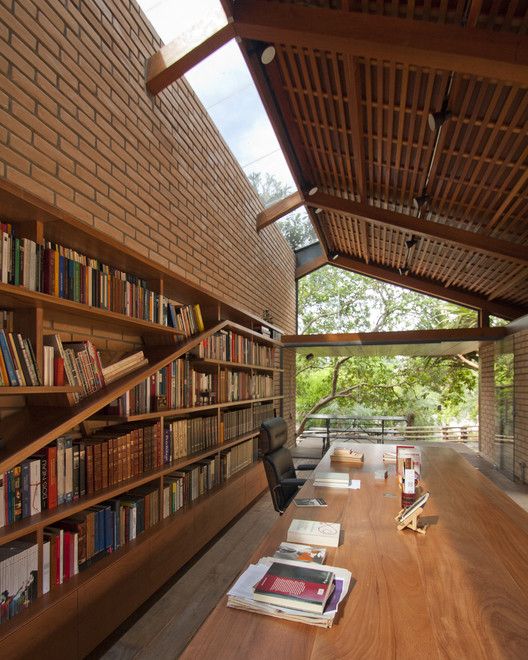 a long wooden table topped with books under a roof