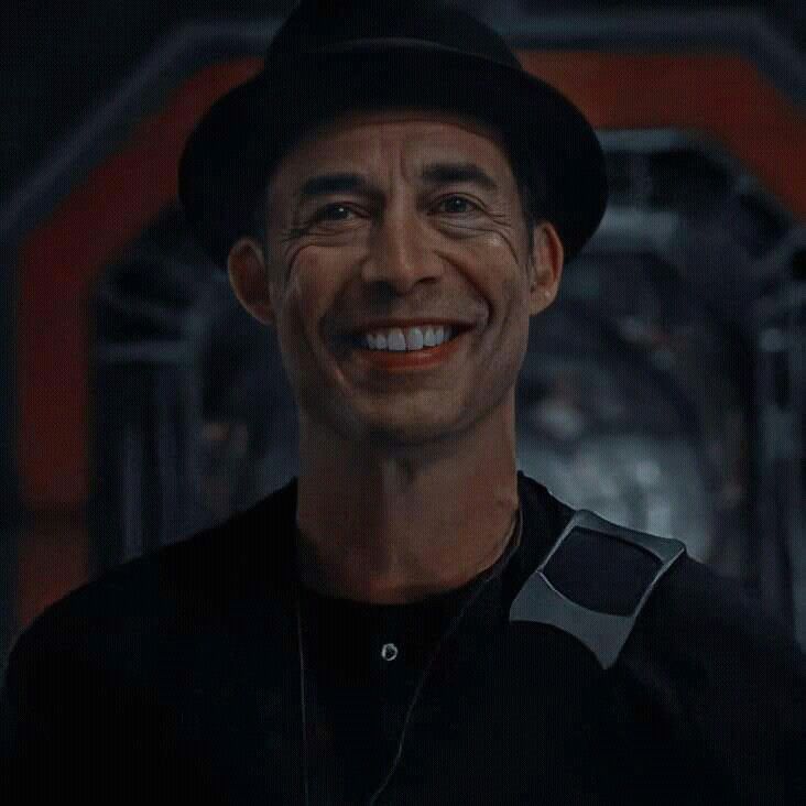 a smiling man in a black shirt and hat with a smile on it's face