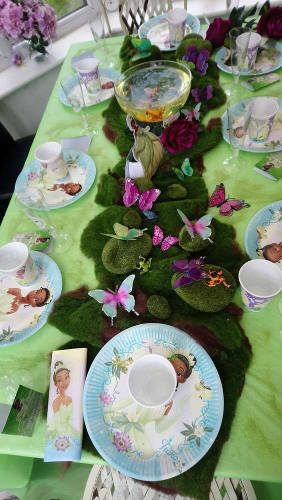 the table is set with plates, cups and saucers on moss covered placemats