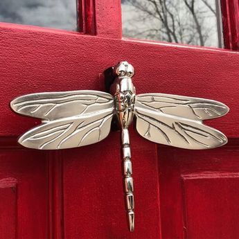 a metal dragon door knocker on a red door