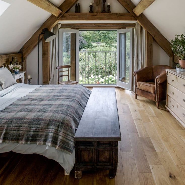 a bedroom with a bed, dresser and window in the atticed room that has wooden beams