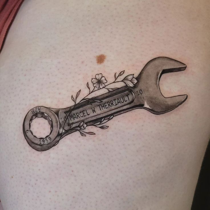 a tattoo with a wrench and flowers on it