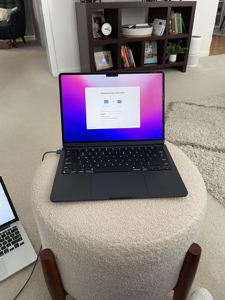 an open laptop computer sitting on top of a white ottoman