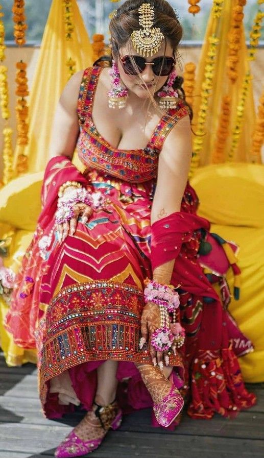 a woman in a red and gold dress sitting on a wooden floor next to flowers