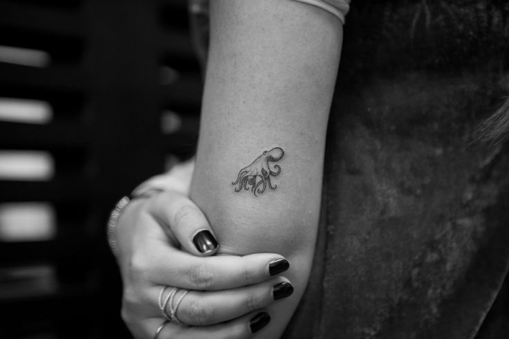 a woman's arm with an octopus tattoo on the left side of her arm