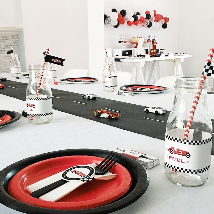 the table is set with red and black plates, silverware, and mickey mouse napkins