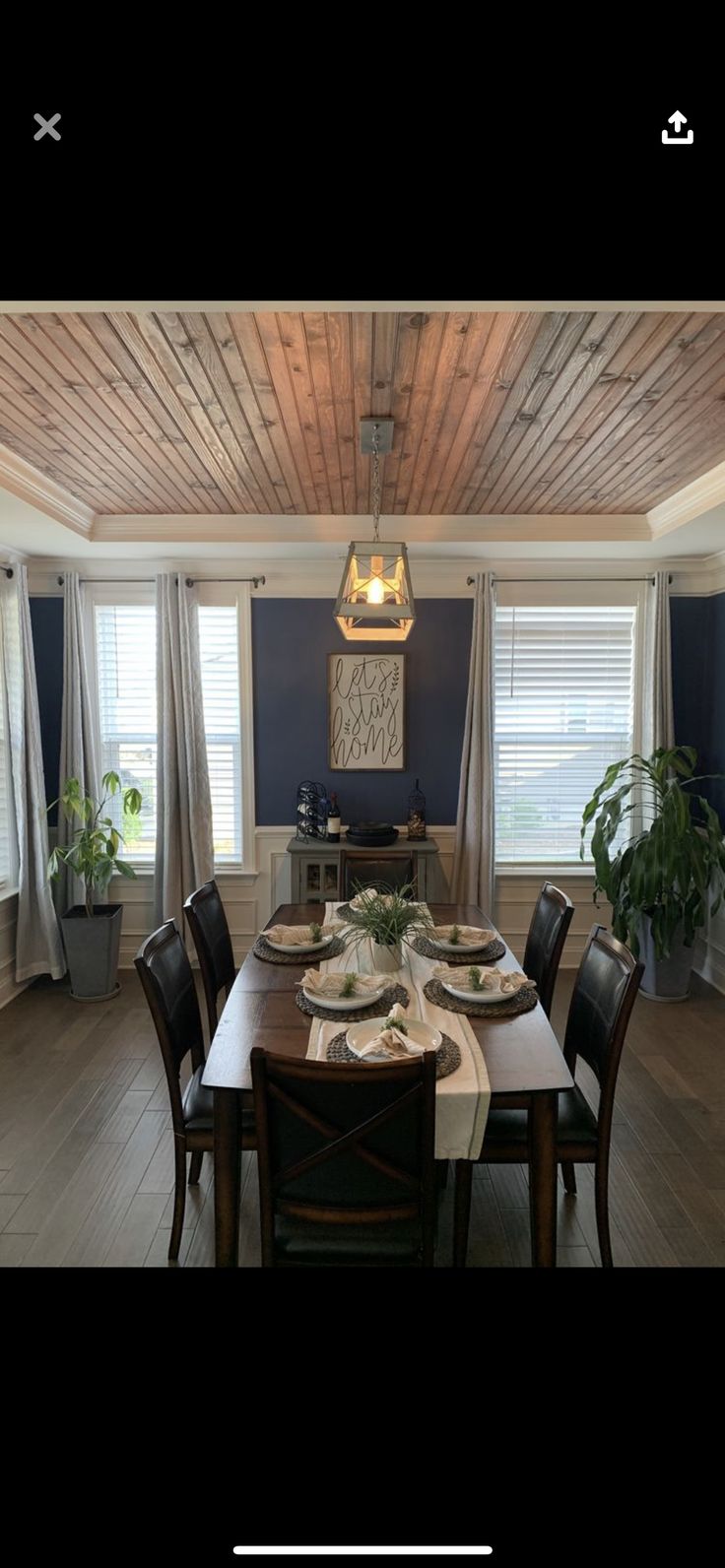 the dining room table is set for four with place settings on each plate, along with two potted plants