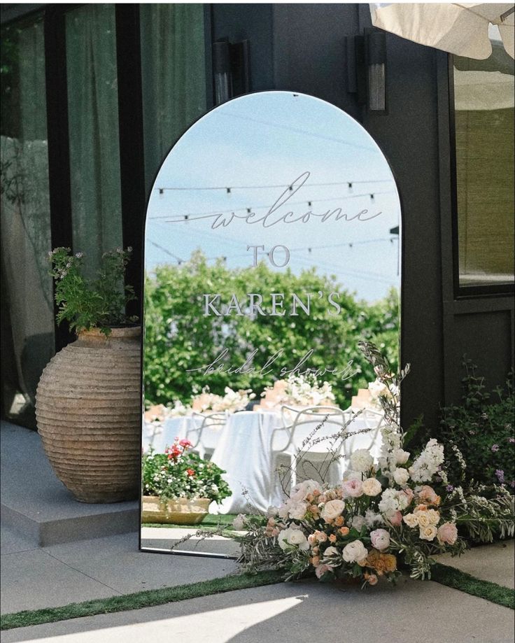 a large mirror sitting on the side of a building next to a flower pot and table