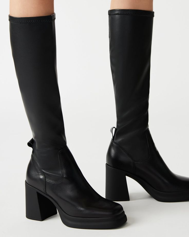 The ZENOVIA square toe knee boot is set on a wide outsole with a block heel, a comfortable base that makes this sleek and defined style super wearable. Block heel square toe knee boot Slip-on style with stretch fabric and a back pull loop 3.25 inch heel height 1 inch platform Size 6 measurements: 12 inch shaft circumference, 14.5 inch shaft height Size 8 measurements: 13.5 inch shaft circumference, 15 inch shaft height Size 10 measurements: 14 inch shaft circumference, 15.5 inch shaft height Veg Black Square Toe Boots, Steve Madden Store, Apparel Merchandising, Chunky Heels Boots, Square Toe Boots, Leather Socks, Knee Boot, Black Square, Chunky Heels