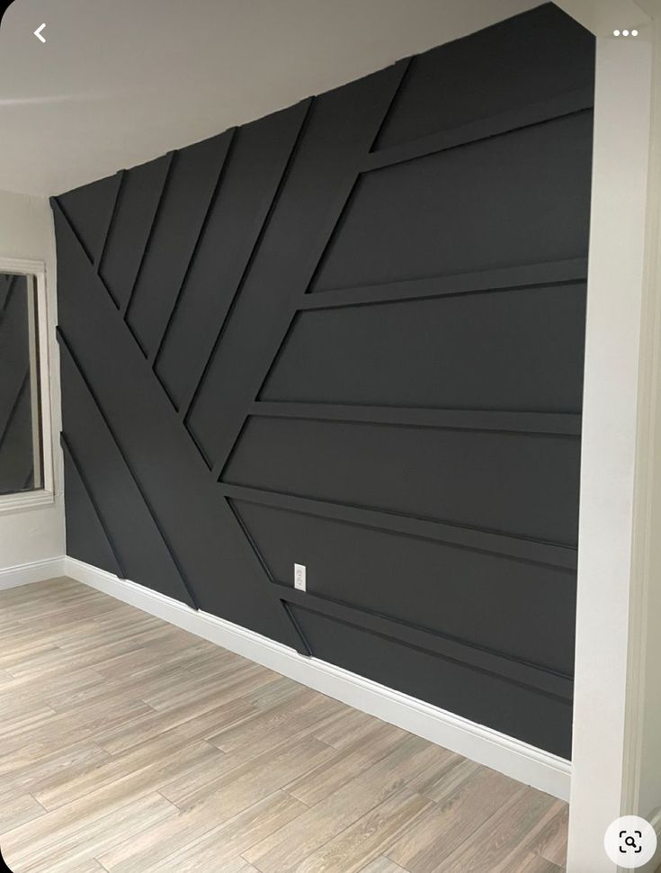 an empty room with wood flooring and black painted wall art work on the walls