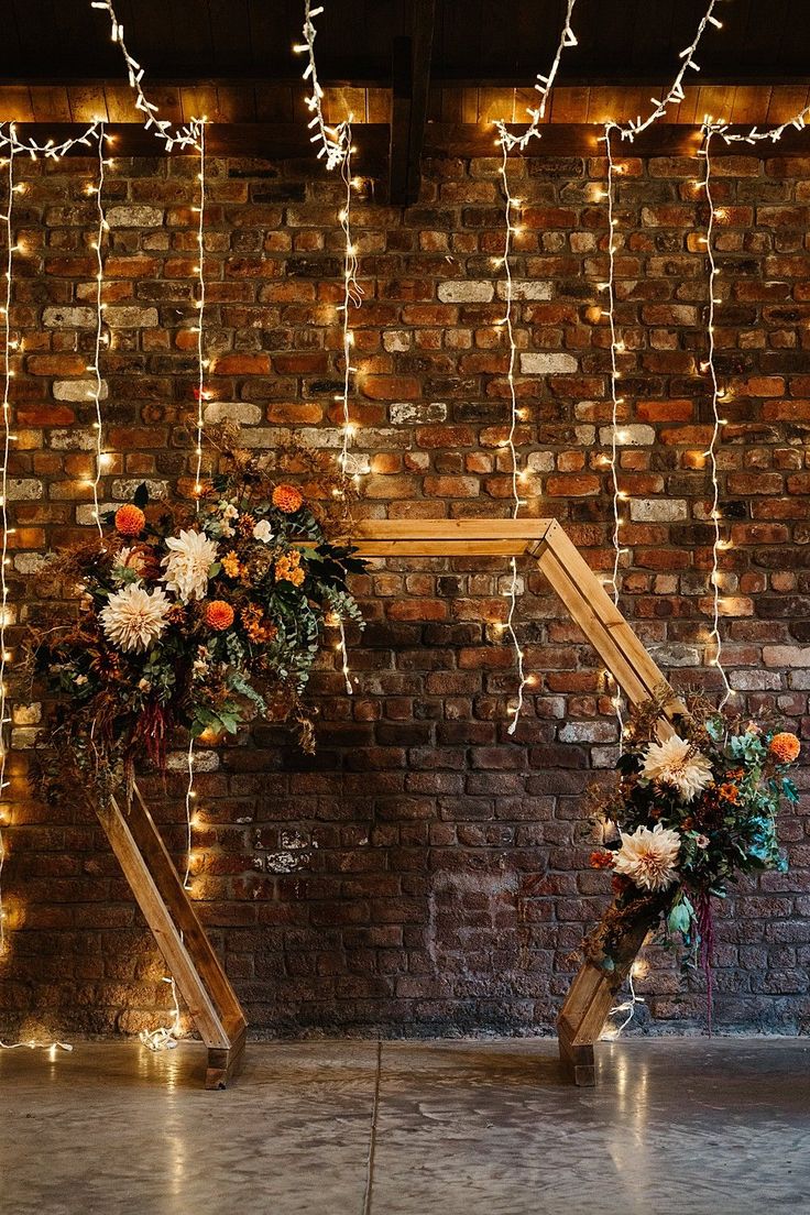 two vases filled with flowers sitting on top of a floor next to a brick wall