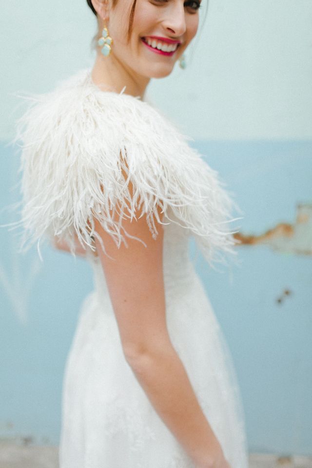 a woman in a white dress with feathers on her shoulders