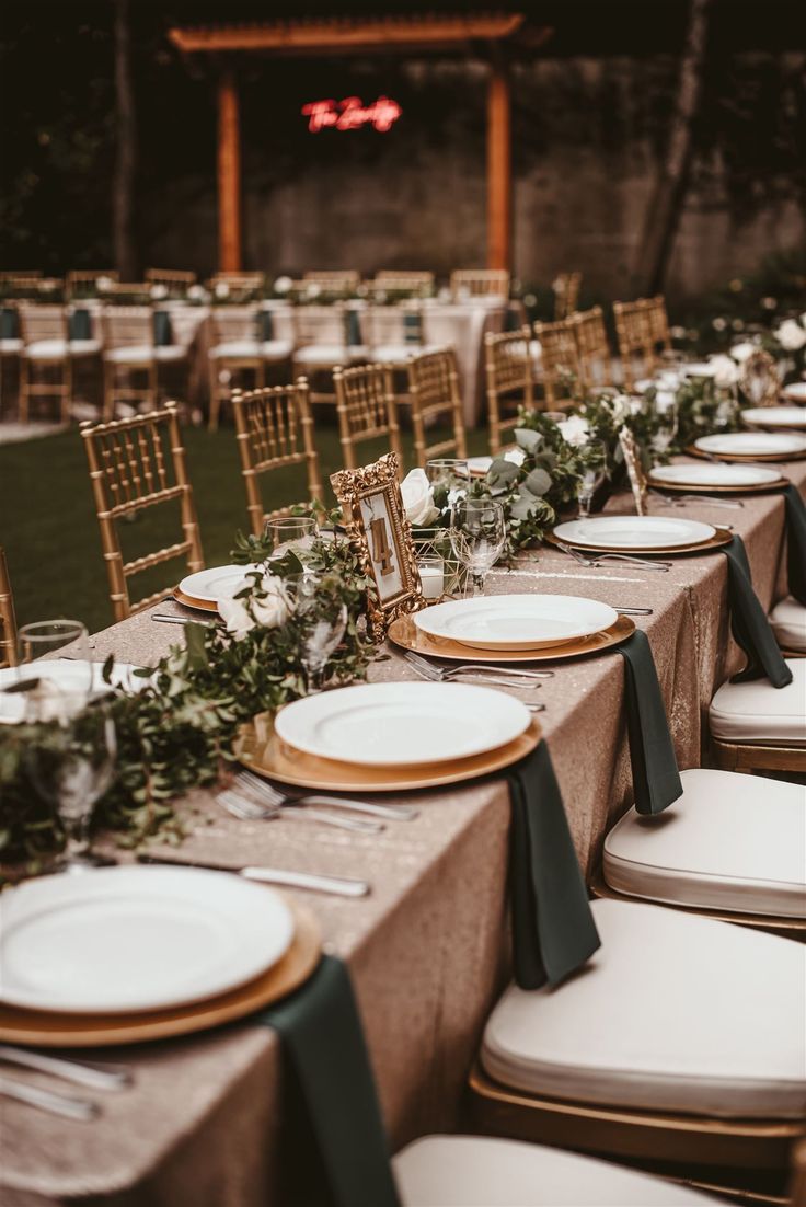 a long table with plates and place settings is set up for an outdoor wedding reception